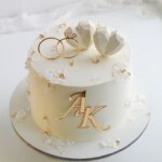 White engagement cake with gold initials.