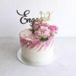 Pink floral engagement cake with topper.