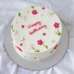 White cake with colorful daisy flower details.